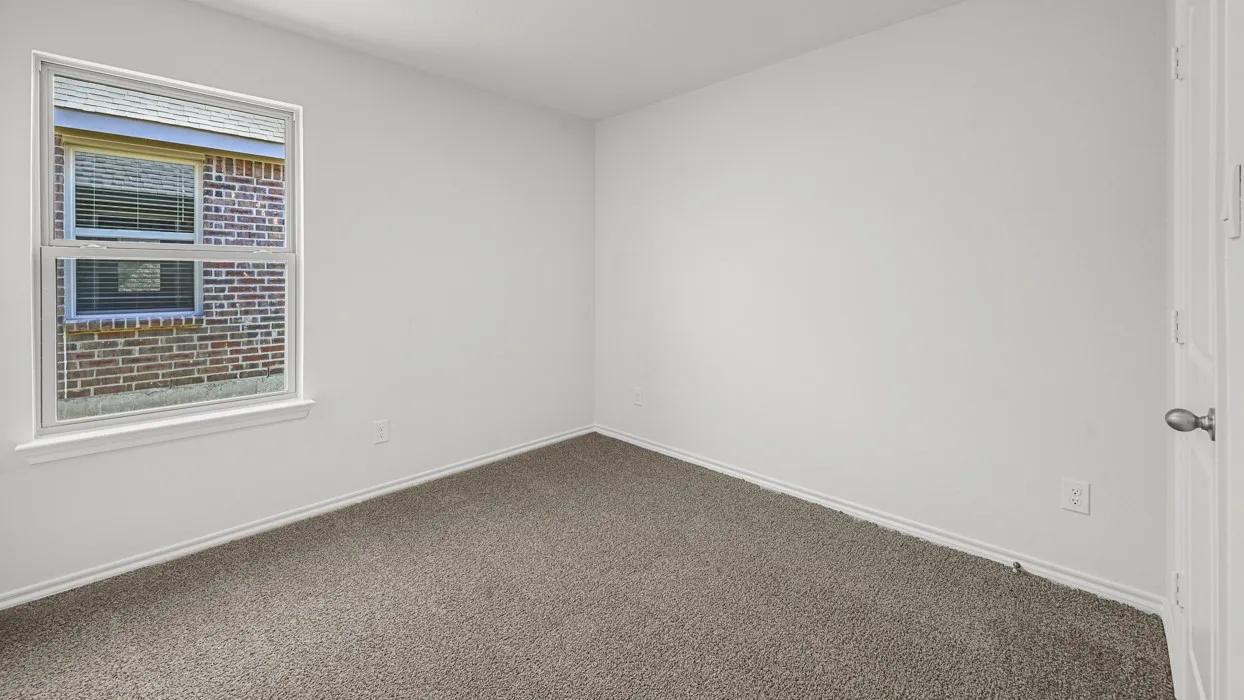 Interior space featuring neutral wall paint, gray carpeting, white baseboards, and a white-framed window