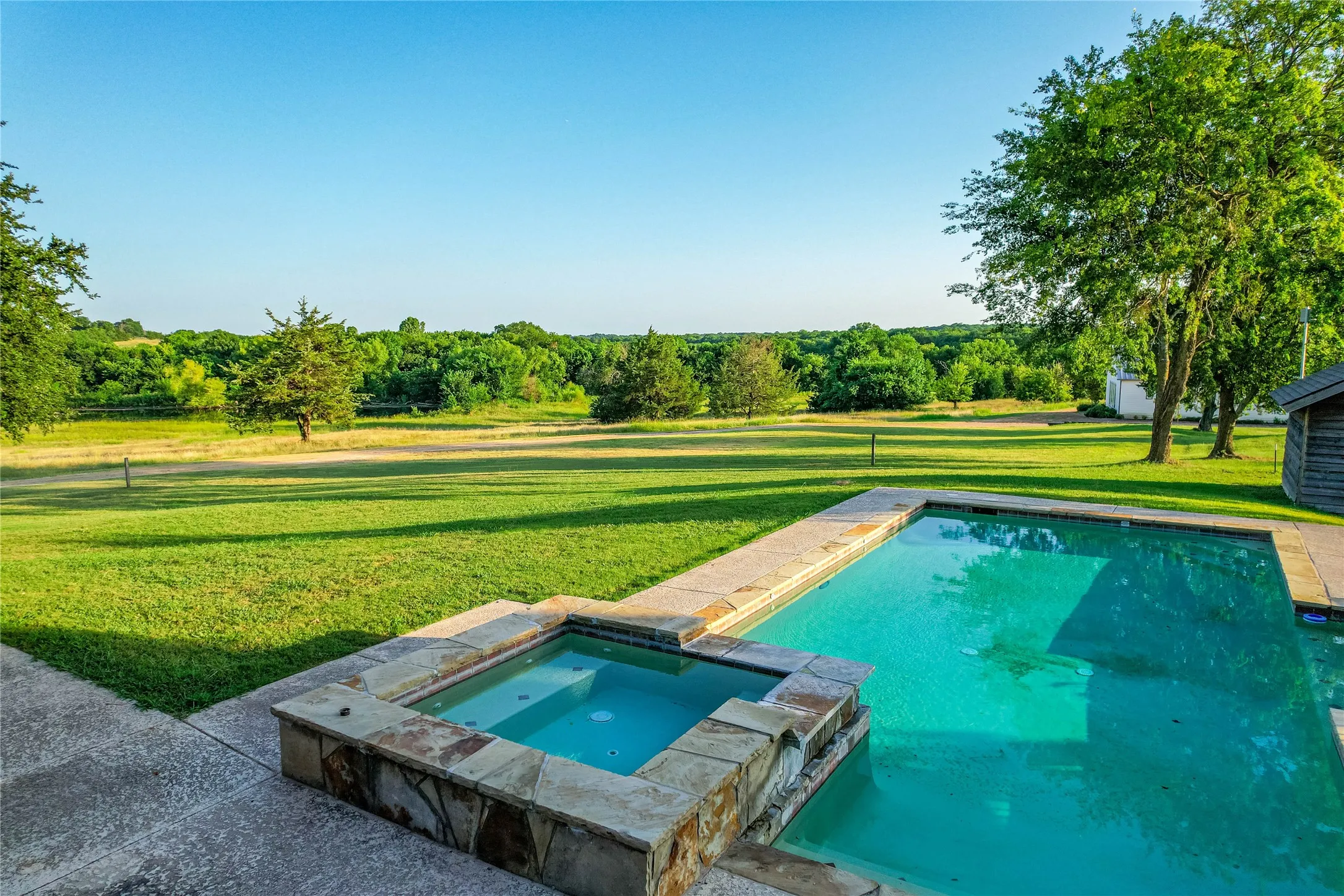 Swimming pool and spa with flagstone coping and stone veneer surround