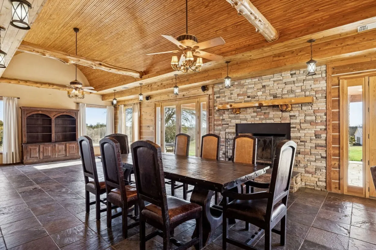 Spacious room featuring wood-paneled ceiling, exposed wood beams, and textured floor tiles