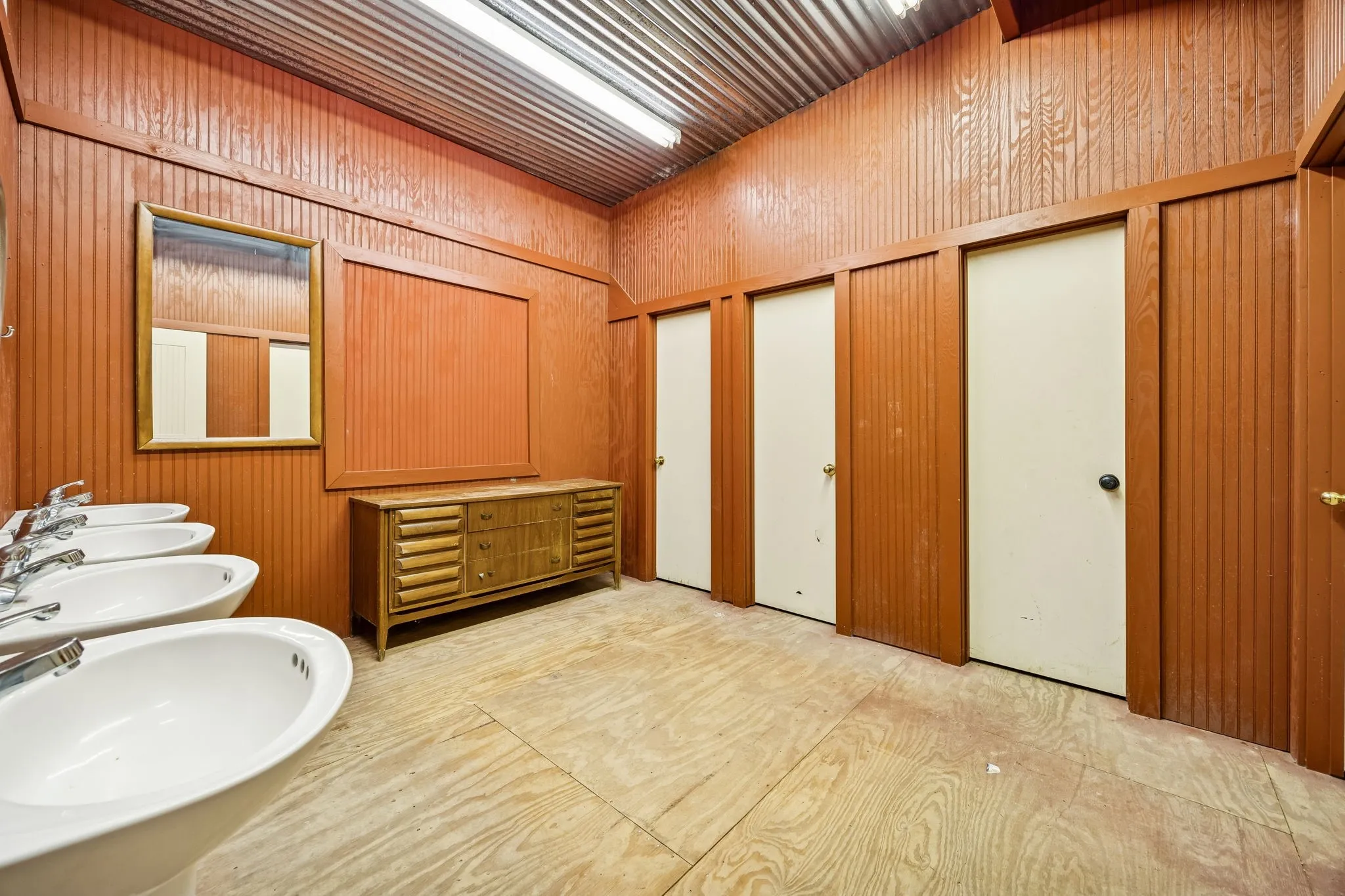 Commercial restroom featuring multiple white pedestal sinks with chrome faucets