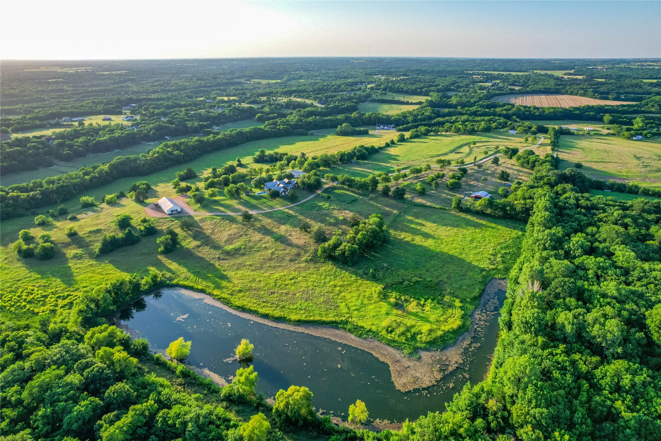 Expansive rural landscape featuring a winding body of water bordered by dense tree lines