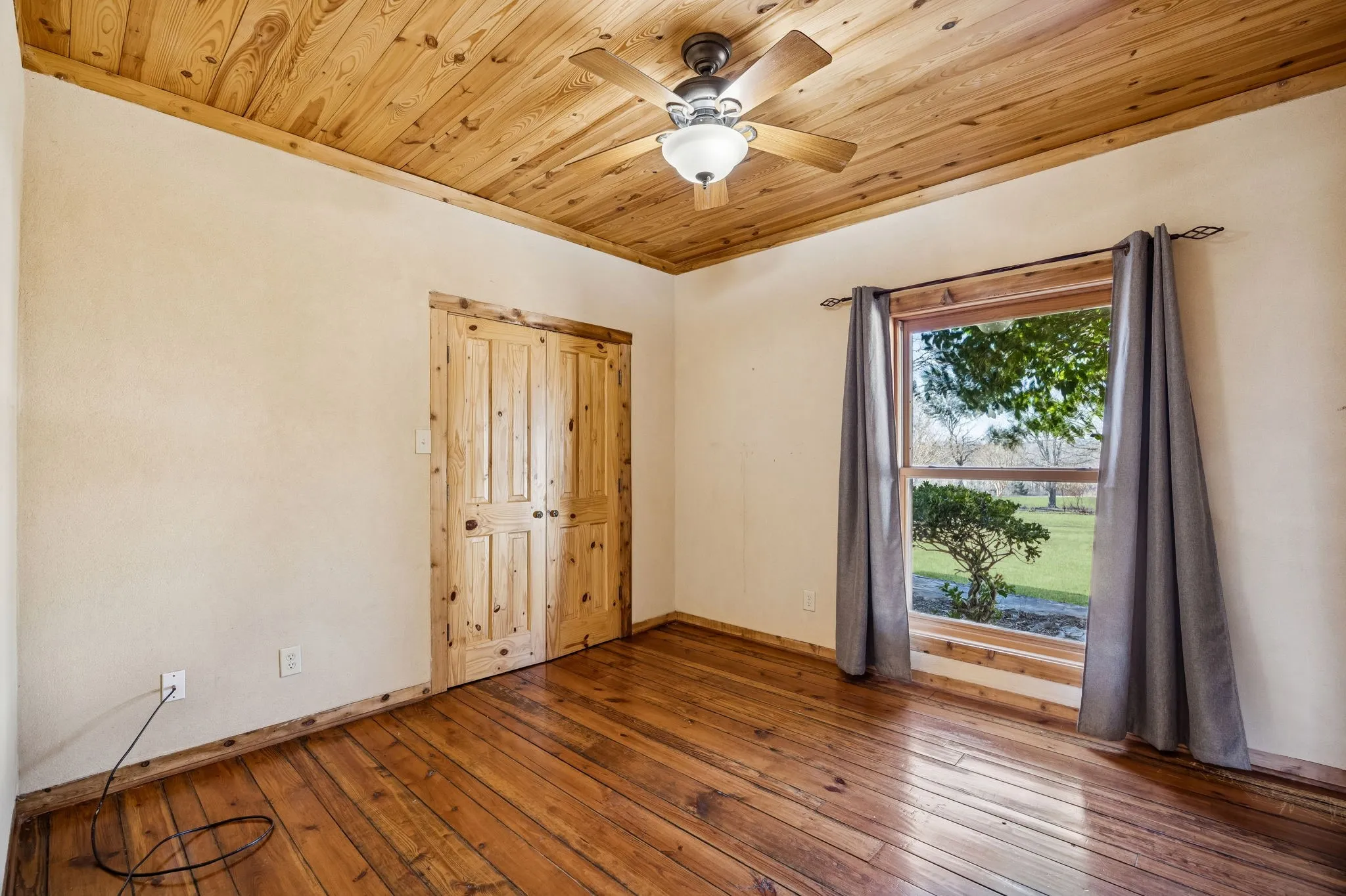 Wood-finish flooring and a wood-paneled ceiling with a central ceiling fan