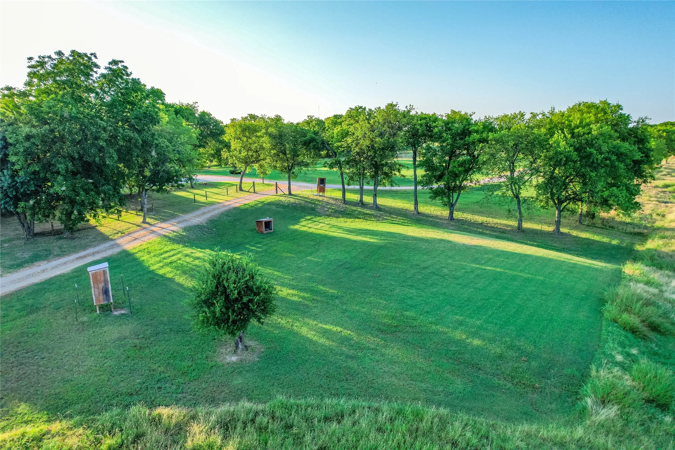 Expansive green lawn with a tree-lined perimeter and natural foliage at the property edge