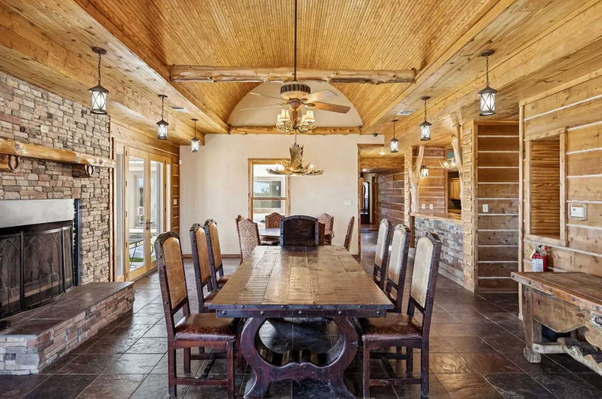 Spacious dining area featuring a stone fireplace, wood-finish flooring, and a vaulted wood-paneled ceiling