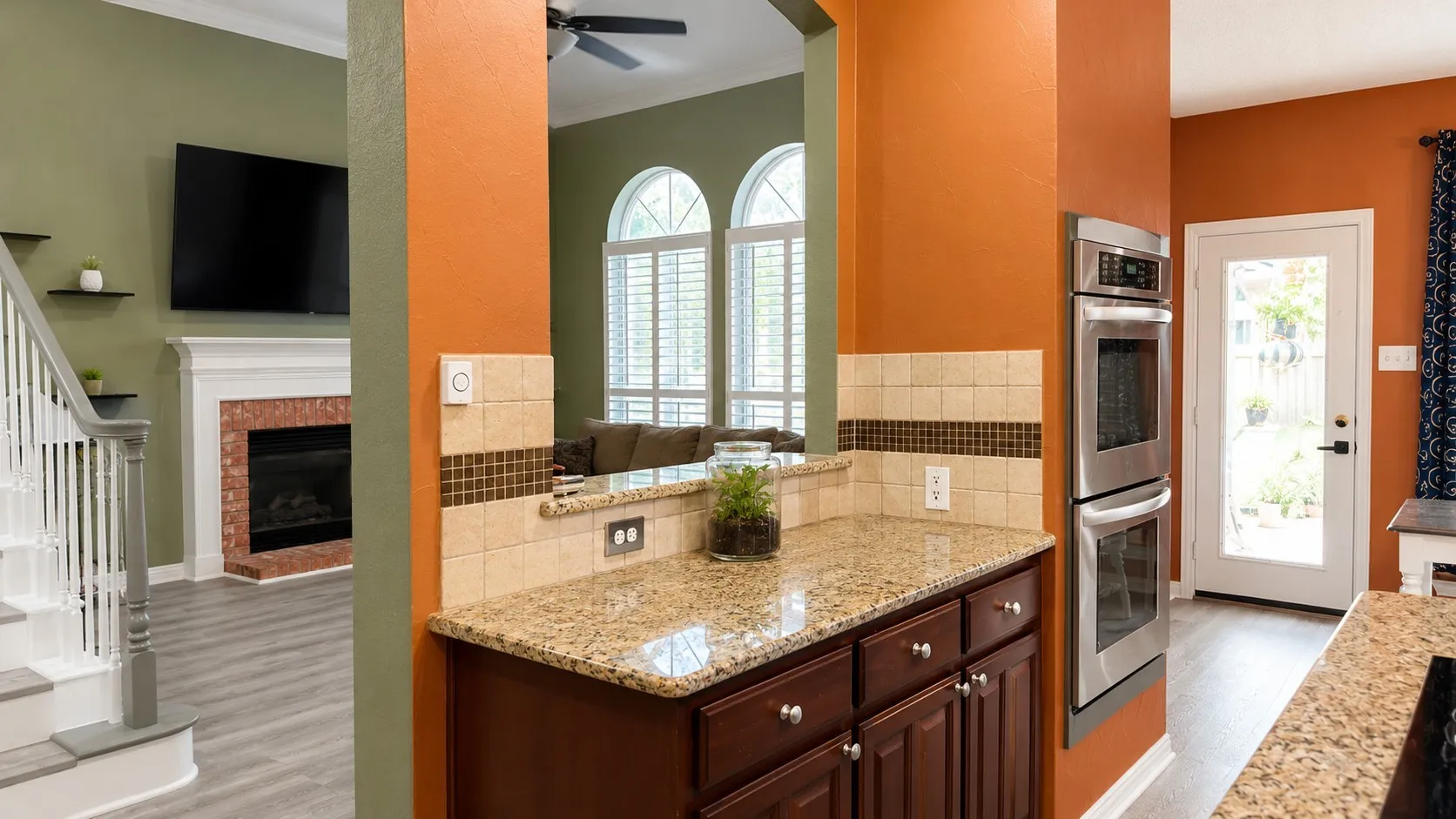 Kitchen counter with granite-finish countertop, dark wood cabinetry, and a tile backsplash featuring a decorative accent stripe