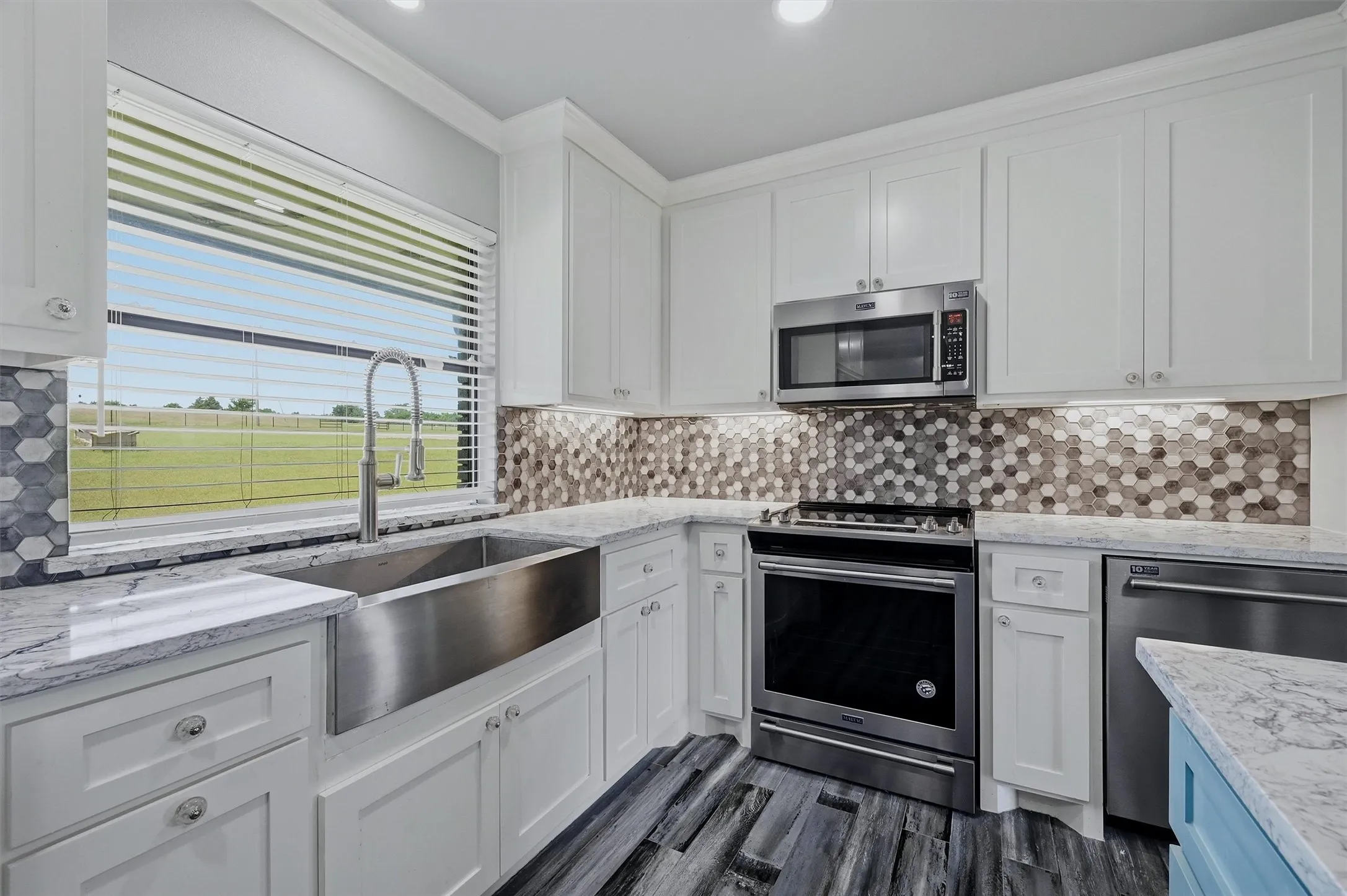 A large farmhouse sink, custom backsplash, and great view of the back pasture can all be found in the kitchen.