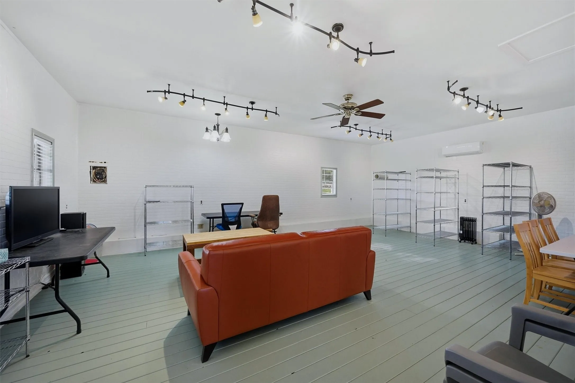 Interior of tool shed -ceiling fan, track lighting and vinyl plank flooring.