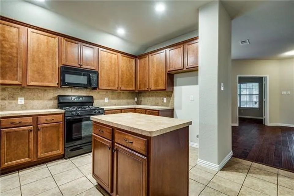 Kitchen featuring warm wood cabinetry, neutral countertops, a tile backsplash, and a central island