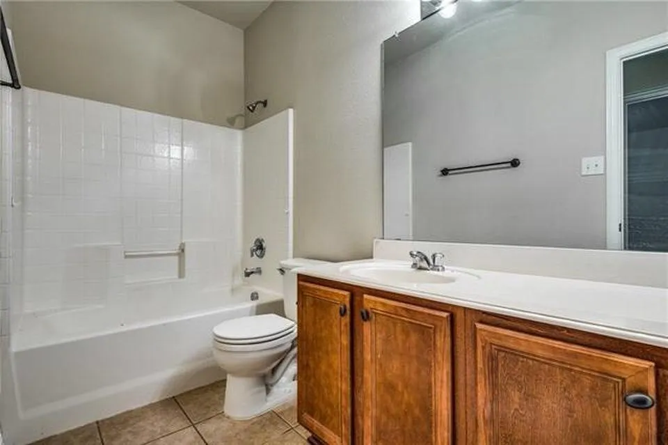Full bathroom featuring a single vanity with wood-finish cabinetry, a white countertop, and a large wall-mounted mirror