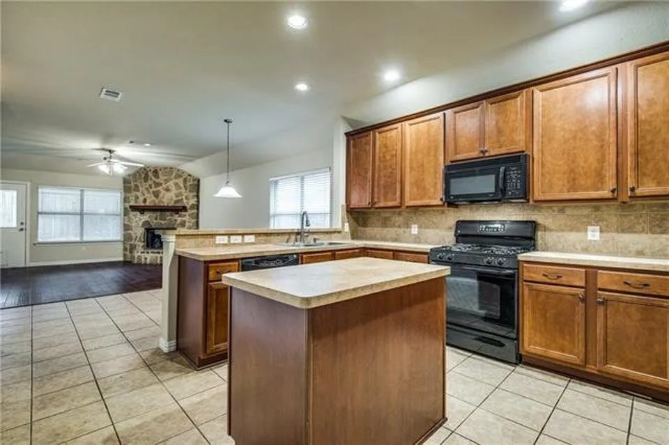 Kitchen featuring wood-finish cabinetry, a black appliance suite, and light-toned countertops