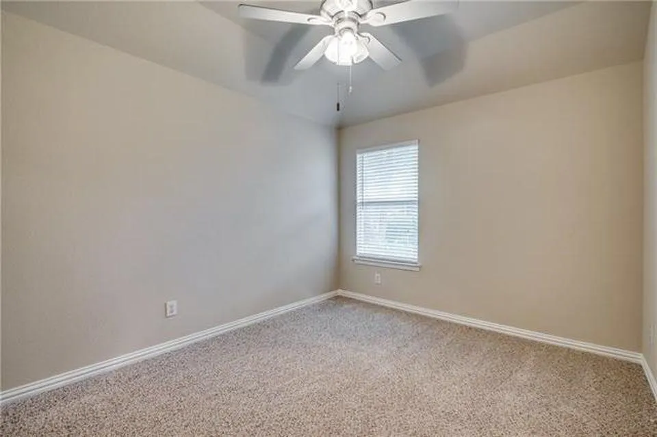 Carpeted room featuring a ceiling fan with integrated lighting, a single window with blinds, and neutral-toned walls