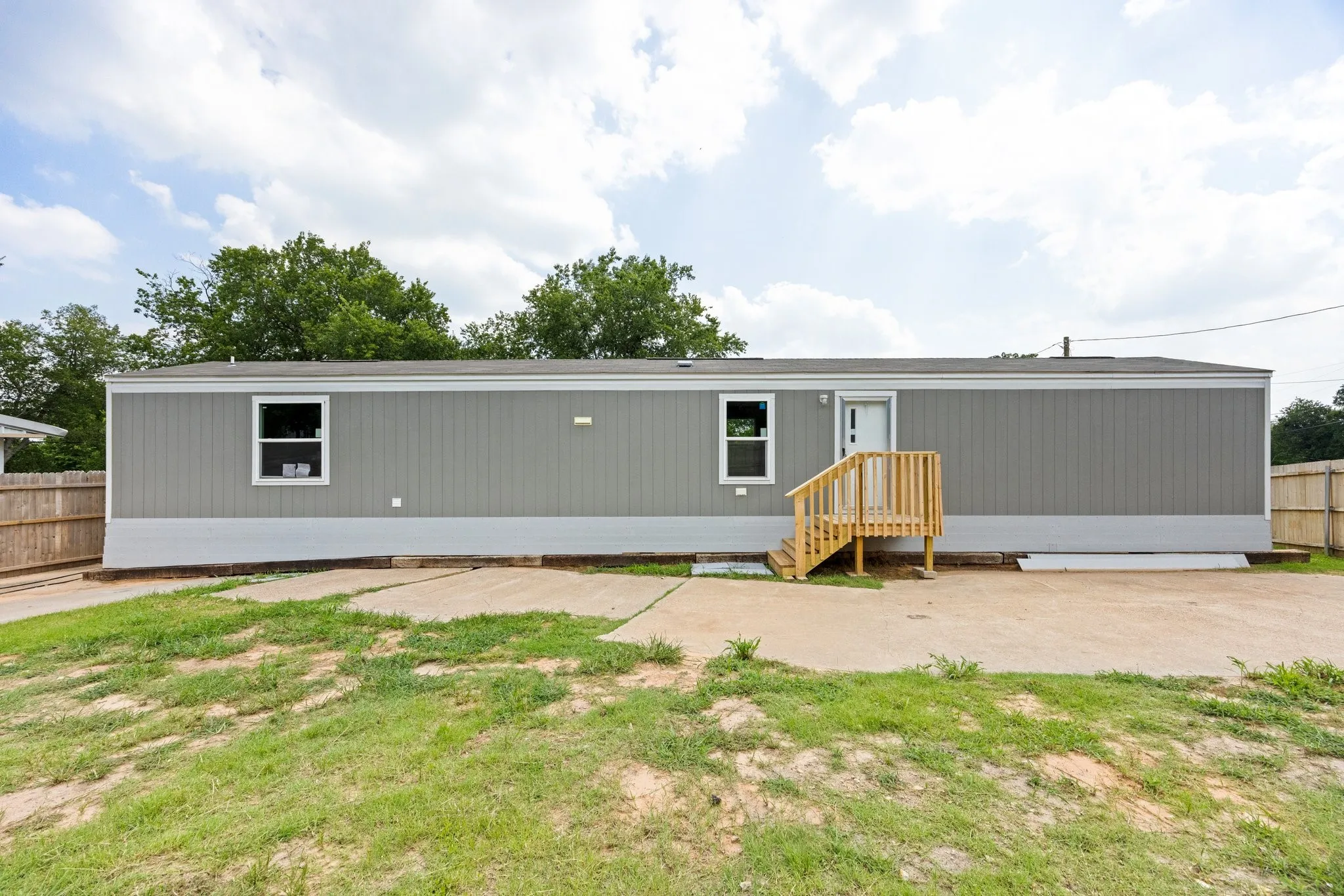 Grey siding exterior with a white front door and wooden porch stairs