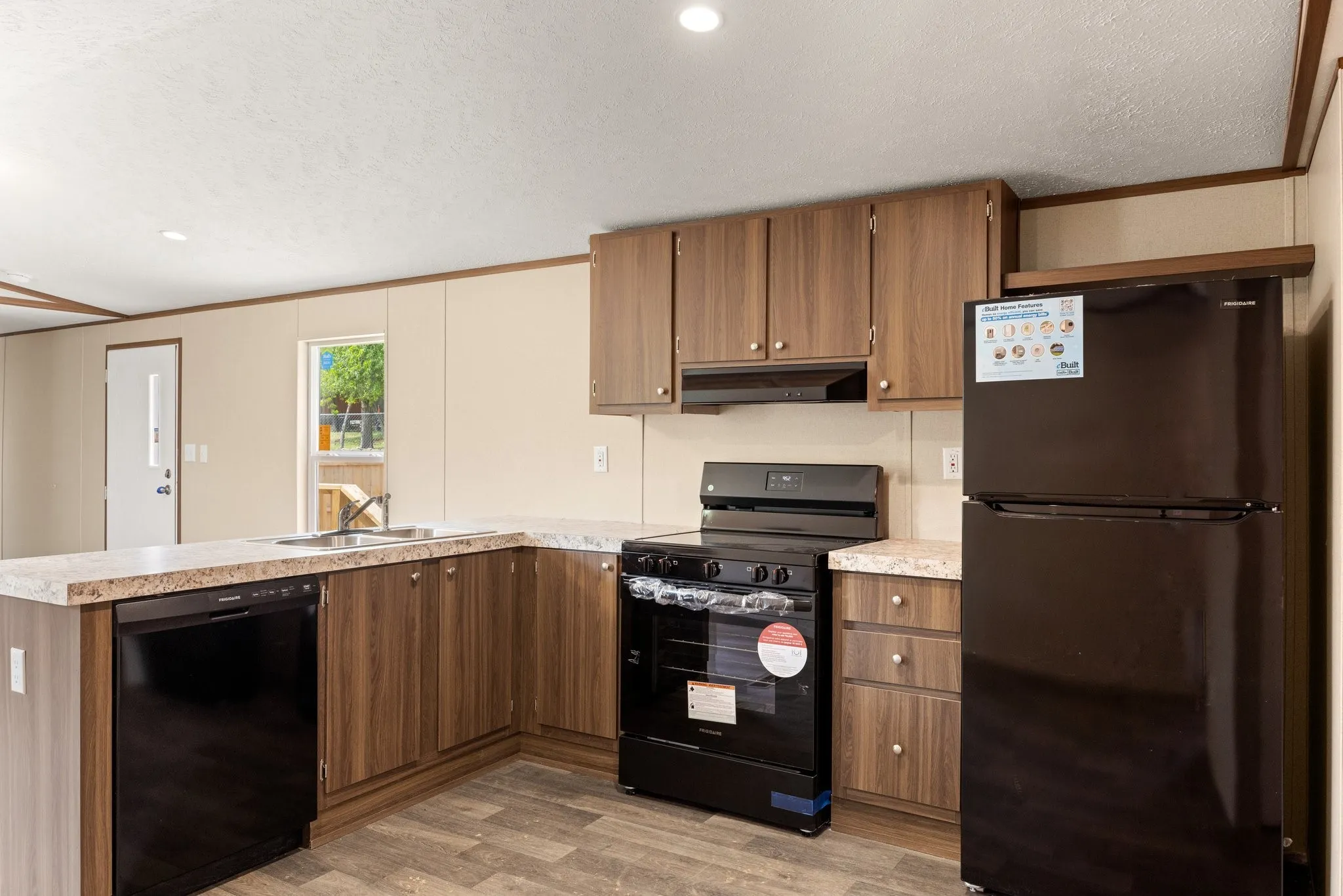 Kitchen featuring wood-finish cabinetry, light-toned countertops, and dark appliance suite