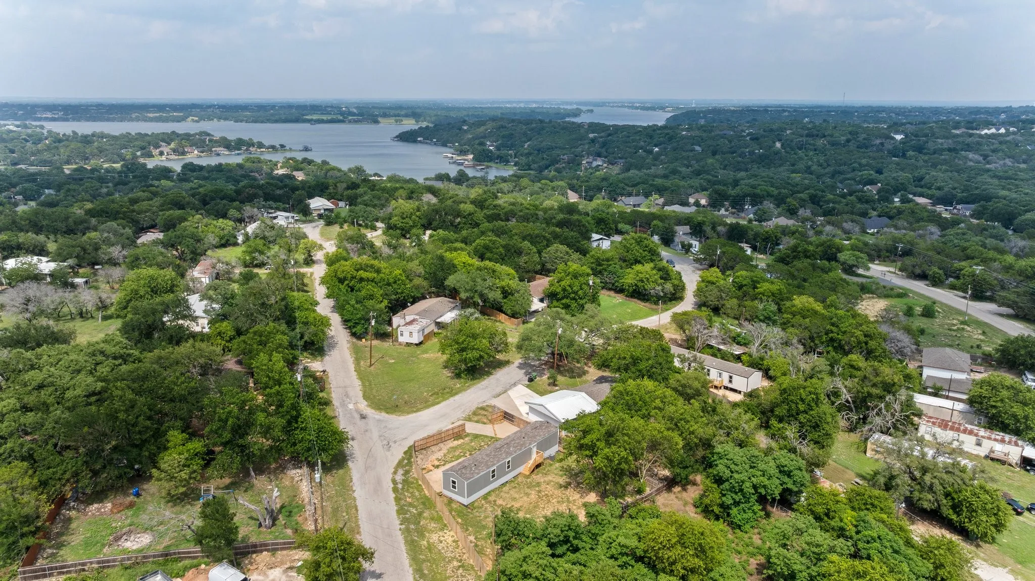 Expansive aerial perspective showcasing a verdant landscape with mature trees, residential properties, and paved roads