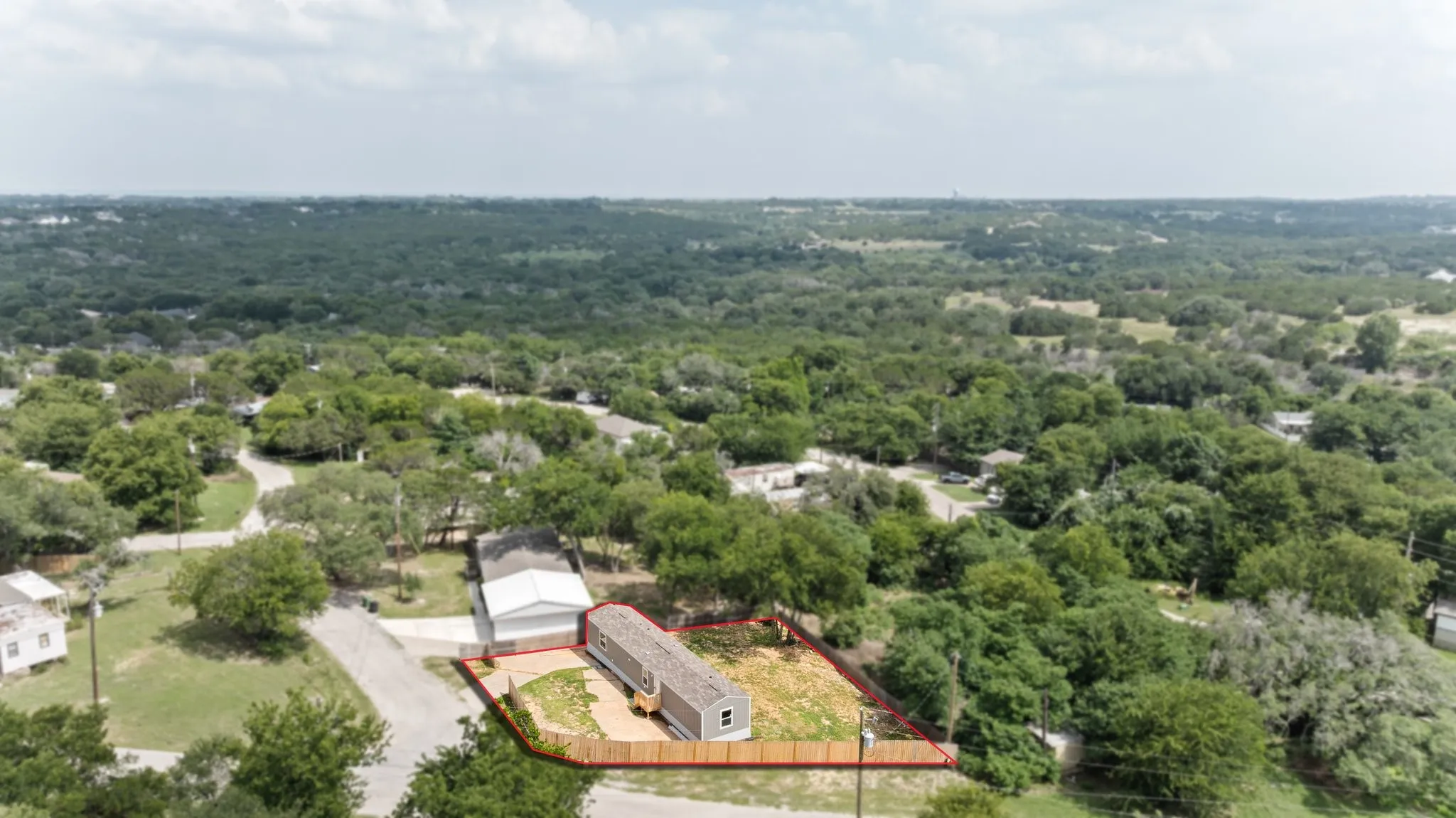 Aerial view showcasing a property with a light-colored exterior and a perimeter fence