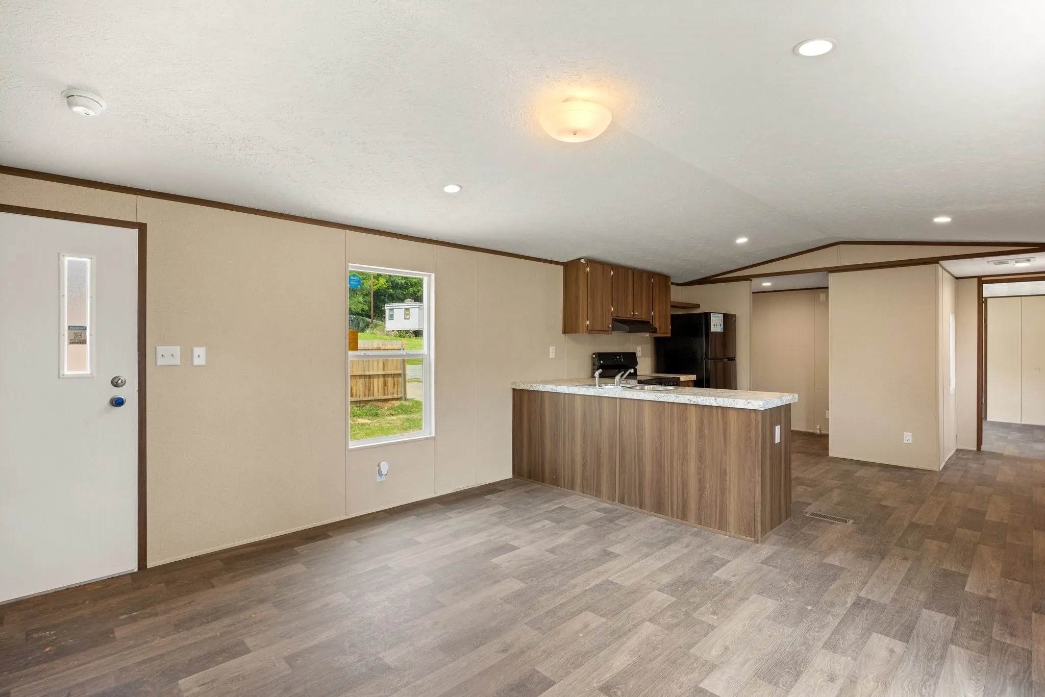 Open-concept living area featuring wood-finish flooring, recessed lighting, and a kitchen island with a stone-look countertop