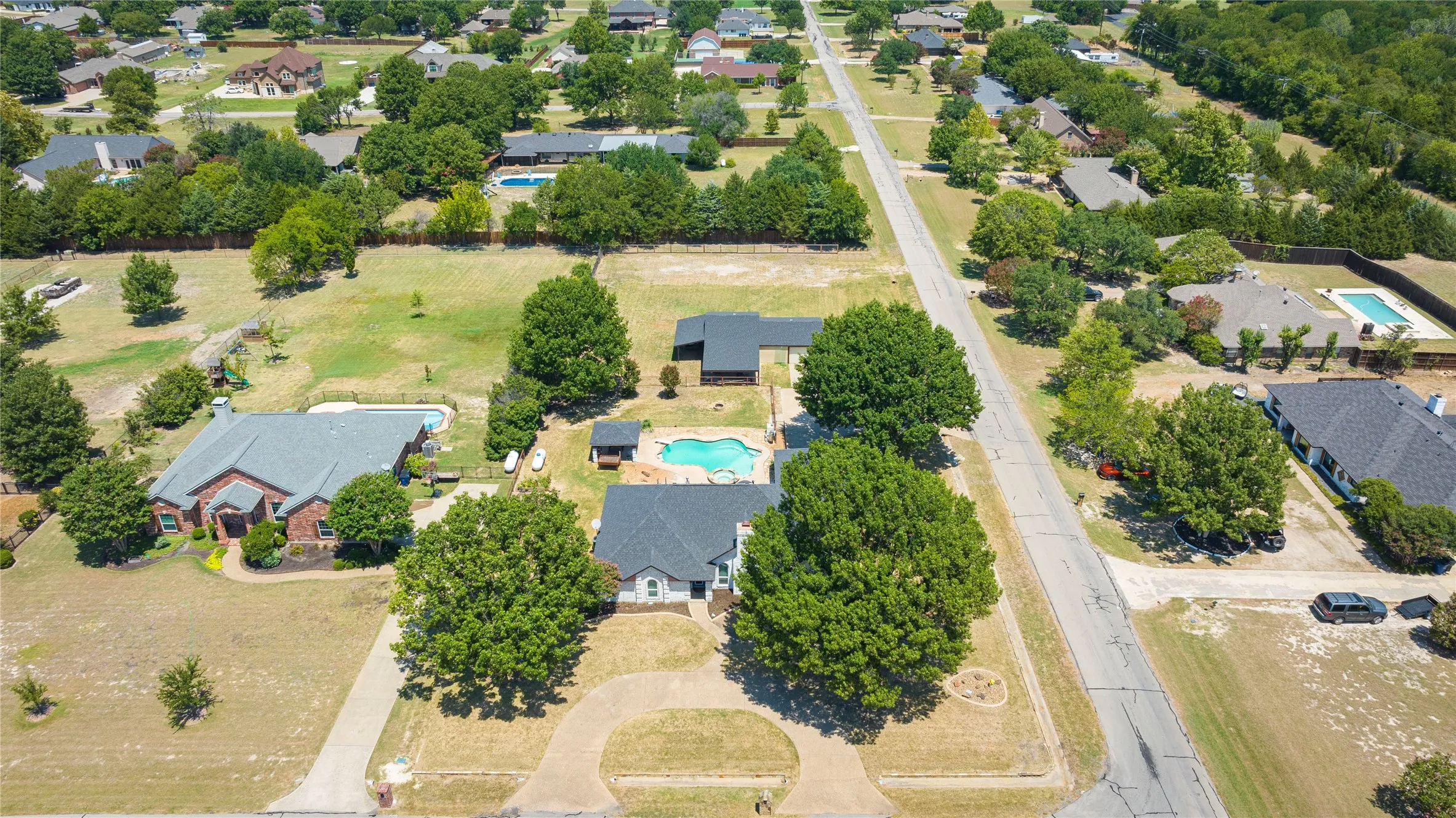 Sprawling residential area featuring numerous properties with private swimming pools and mature trees