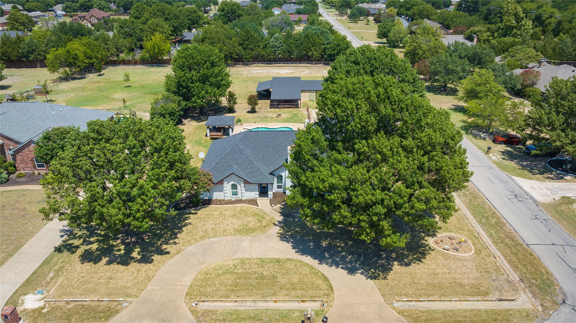 Single-story residence featuring a circular driveway and gour large oak mature trees, on 1 acre lot