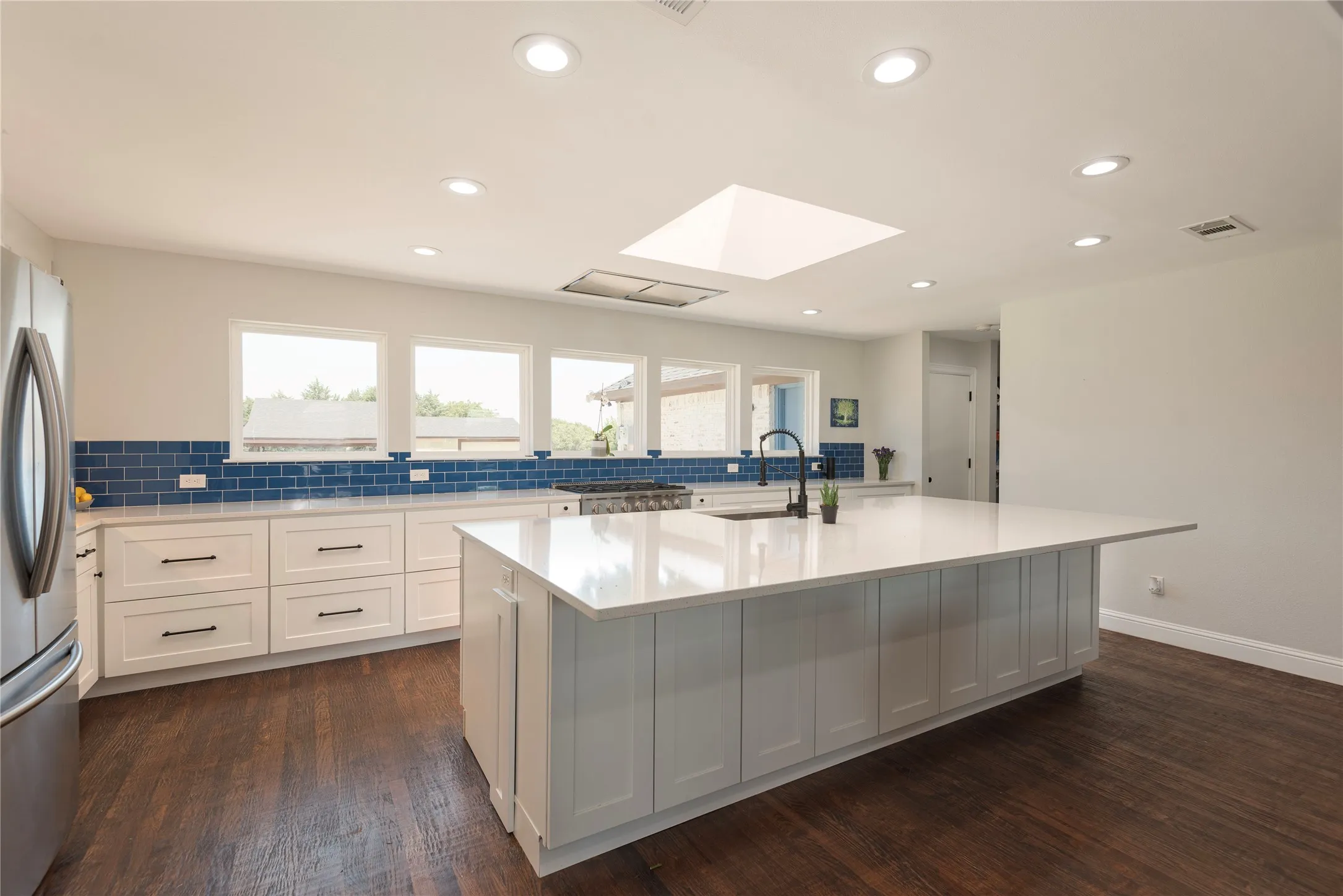 Kitchen featuring a large central island with white countertop, recessed lighting, drawer lower cabinetry, and a skylight