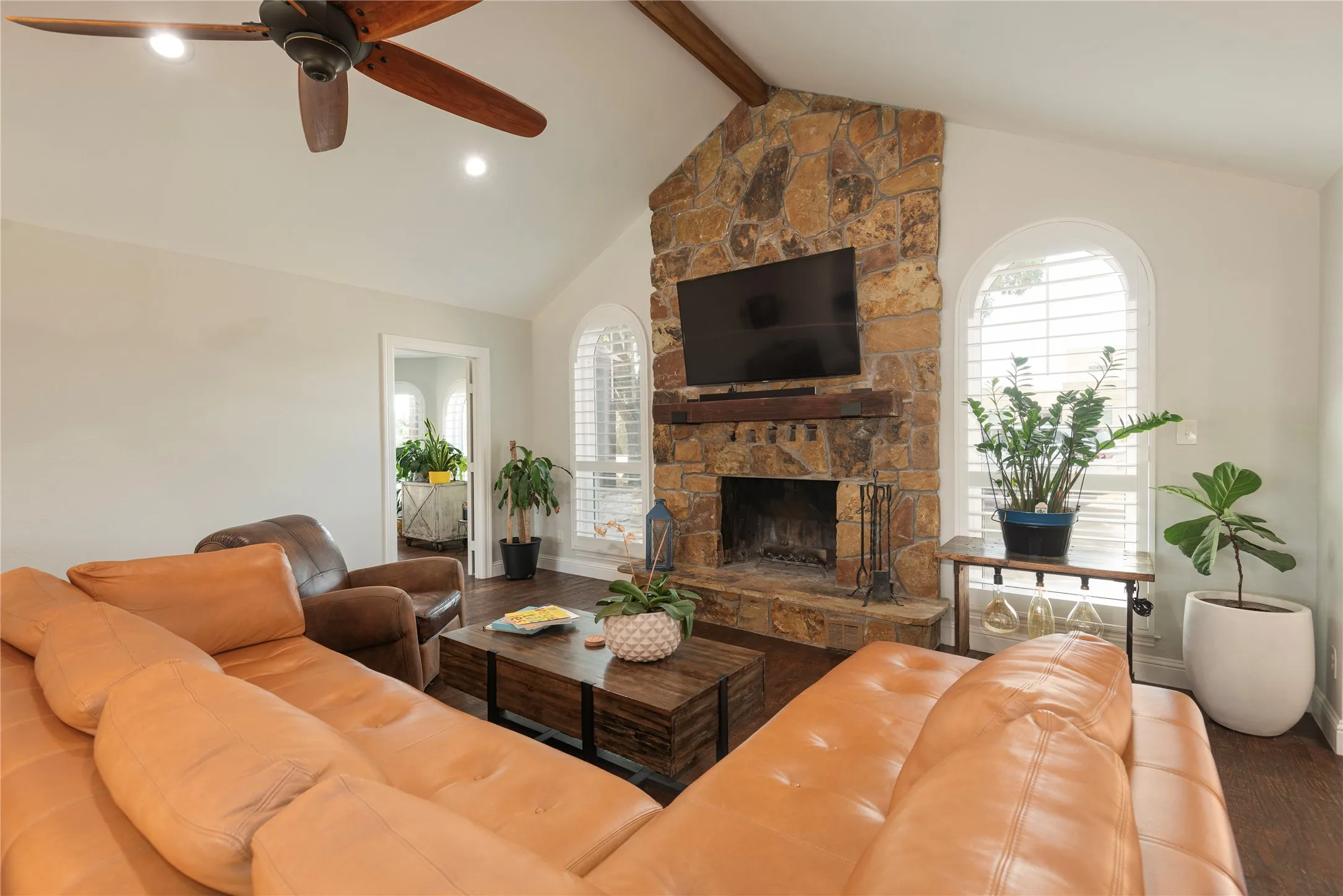 Living area featuring a floor-to-ceiling stone fireplace with Kentucky coal mine beam wood mantle, vaulted ceilings, plantation shutters
