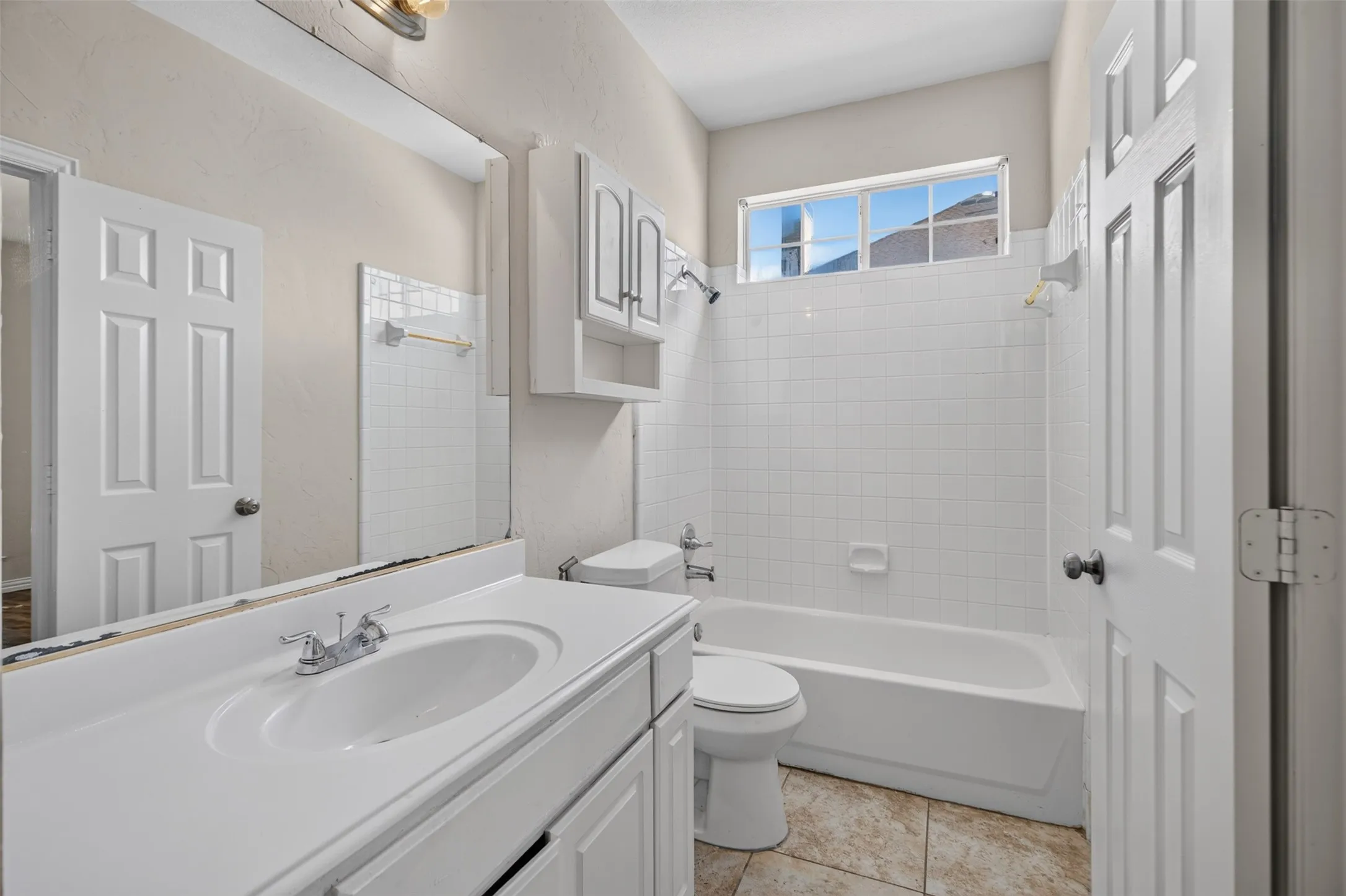 Bathroom featuring a white vanity with integrated sink, chrome faucet, and expansive mirror