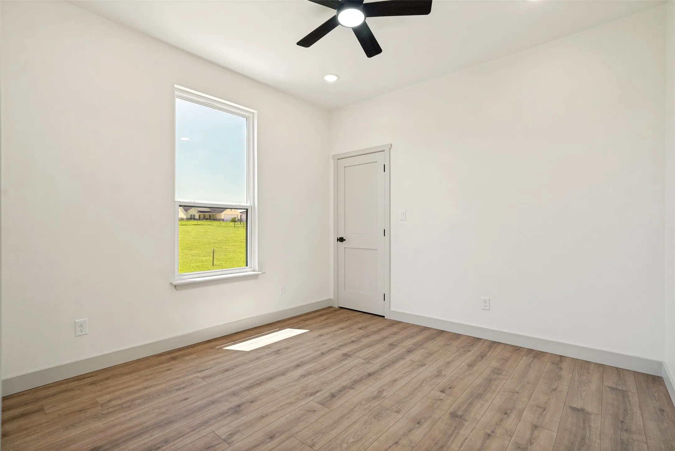 Bedroom 3 featuring wood-finish flooring, white walls, and a single window with a white frame