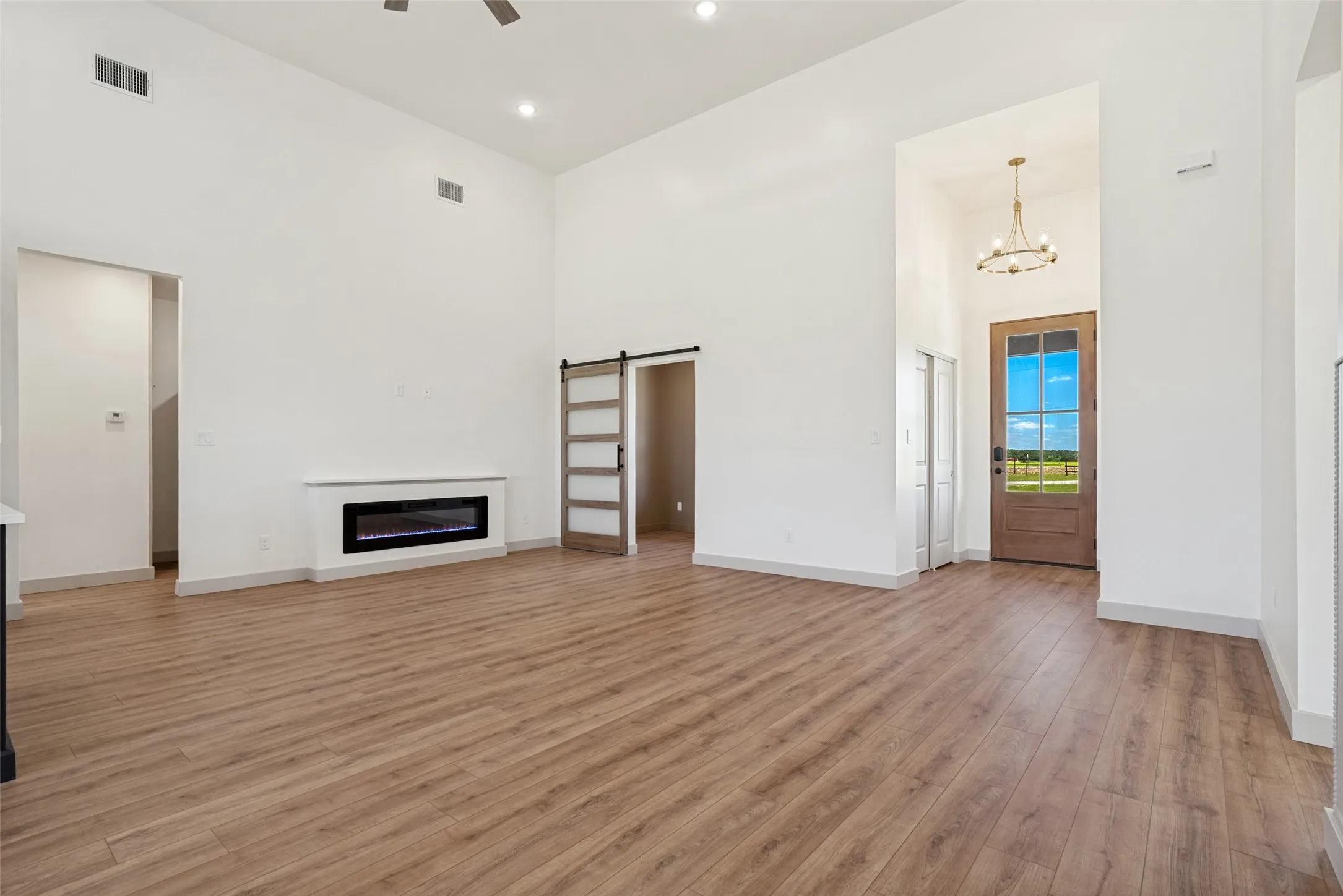 Spacious living area featuring high ceilings, wood-finish flooring, and a built-in electric fireplace