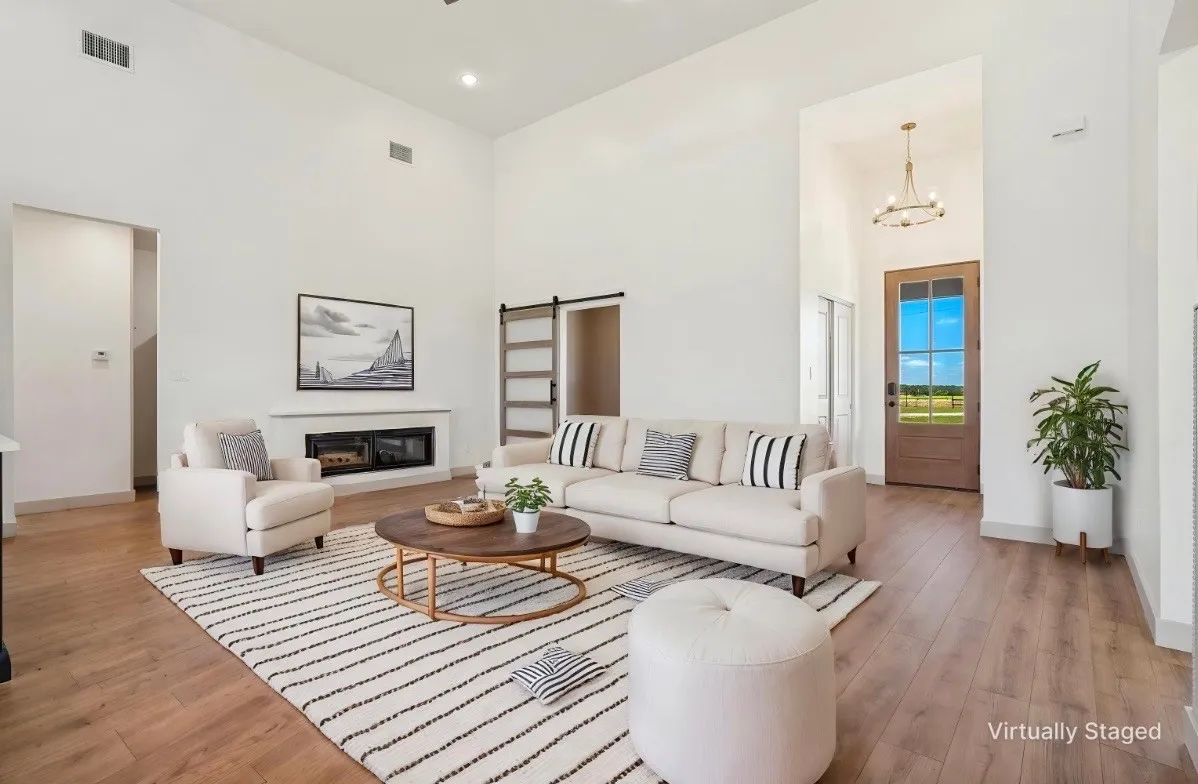 Vaulted ceilings, wood-finish flooring, a built-in fireplace, and a sliding barn door - VIRTUALLY STAGED — FURNISHINGS NOT INCLUDED.