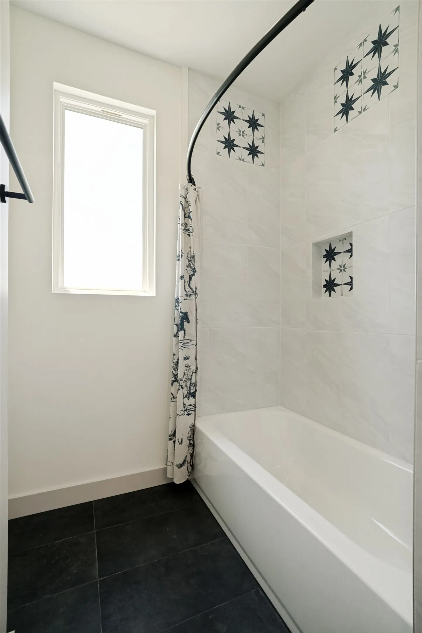 Bathtub and shower combination featuring white subway tile, stunning decorative accent tiles, a shower niche, and a black curved shower rod