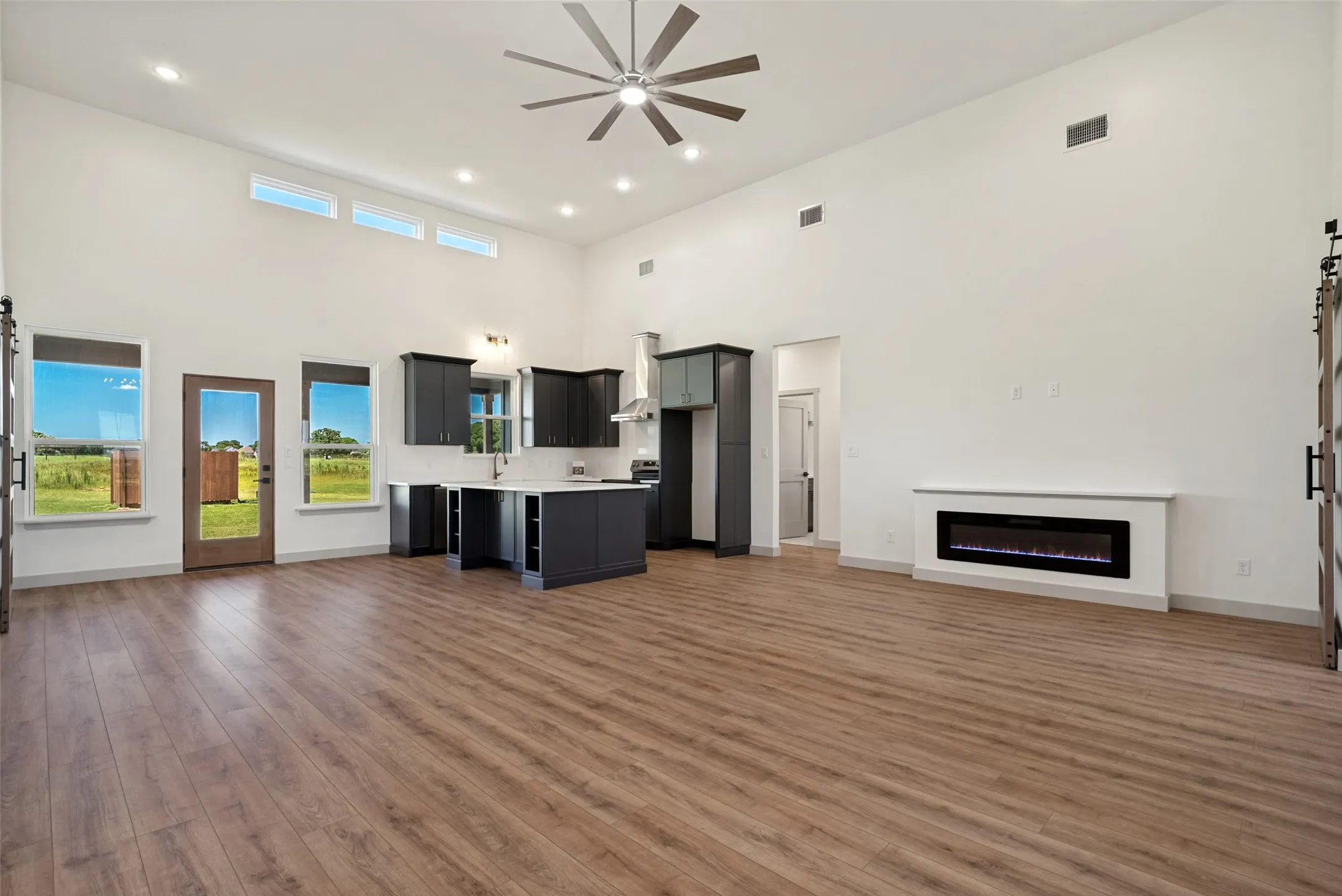 Open-concept living space featuring wood-finish flooring, a contemporary ceiling fan, and recessed lighting