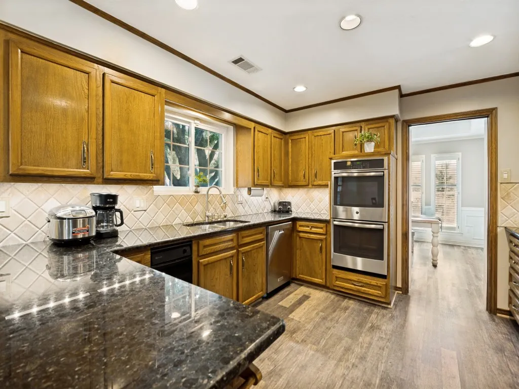 Kitchen featuring wood cabinetry, dark speckled countertops, and stainless steel double ovens