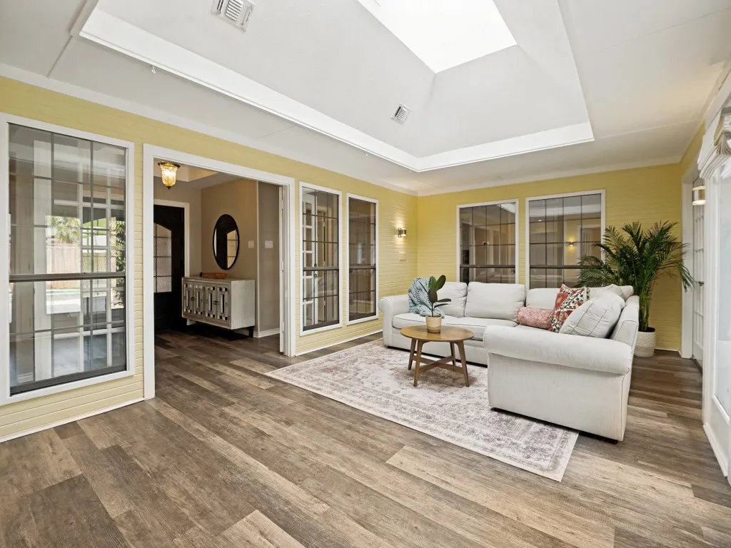 Sunroom featuring a vaulted ceiling with skylight, wood-finish flooring, and multiple gridded windows