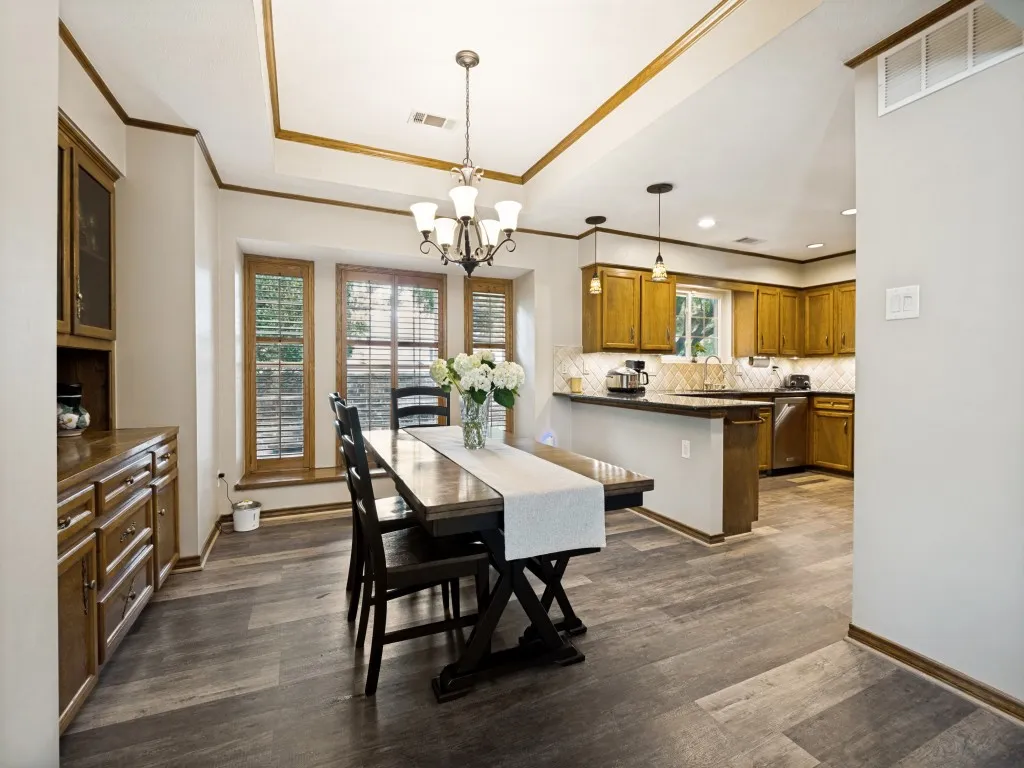 Dining area featuring wood-finish flooring, a tray ceiling with wood trim, and a chandelier
