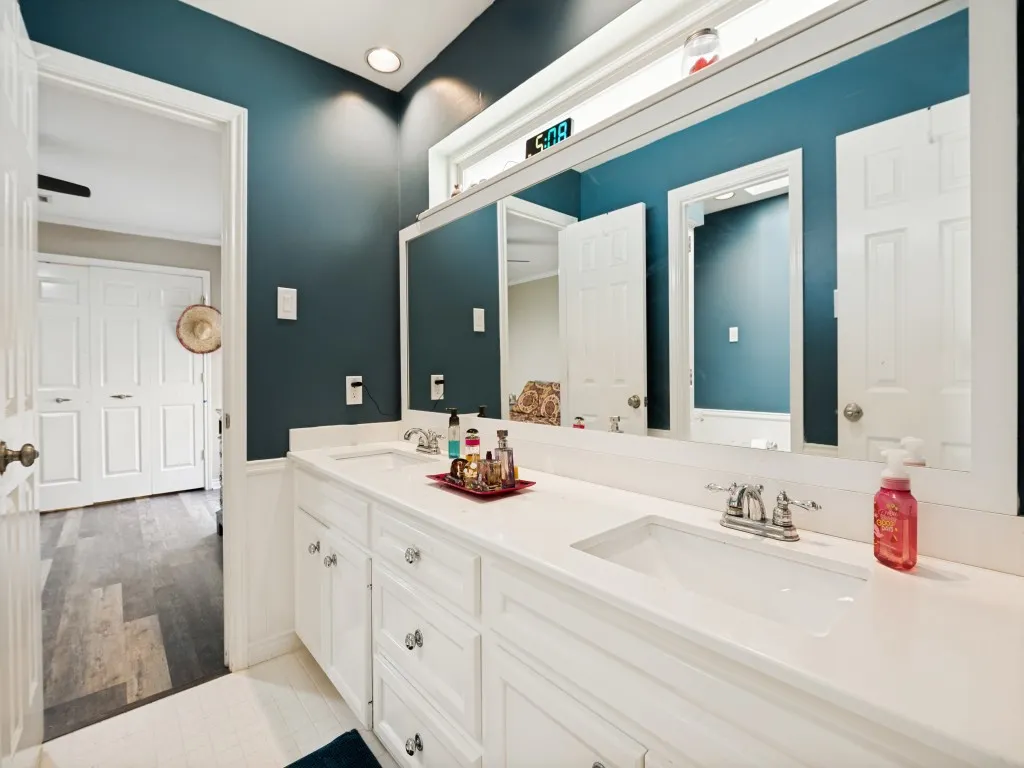 Dual vanity featuring white cabinetry, integrated sinks, chrome faucets, and a full-width mirror