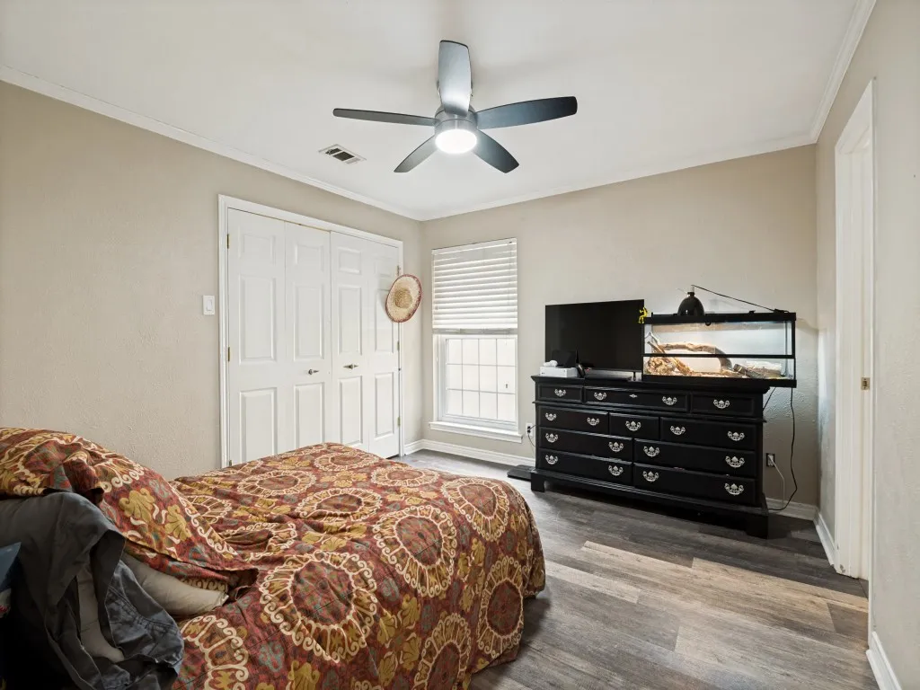 Interior space featuring wood-finish flooring, a ceiling fan with integrated lighting, and a white-trimmed window with blinds