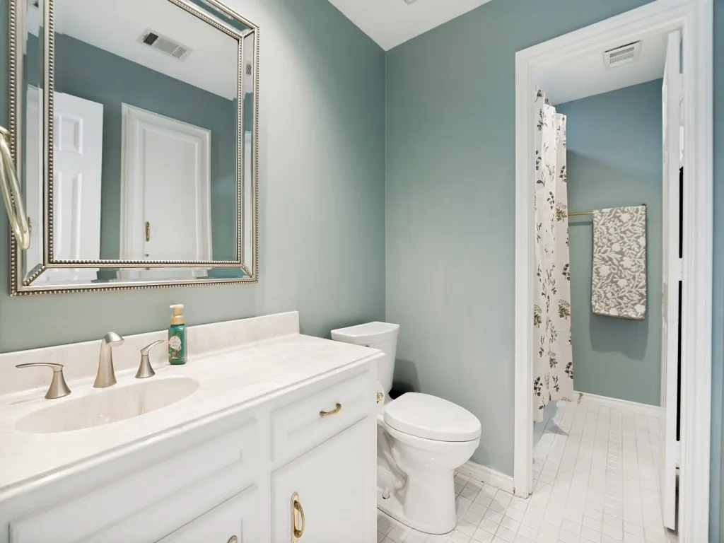 Bathroom featuring a white vanity with an undermount sink, brushed nickel faucet, light-toned countertop, and white tile flooring