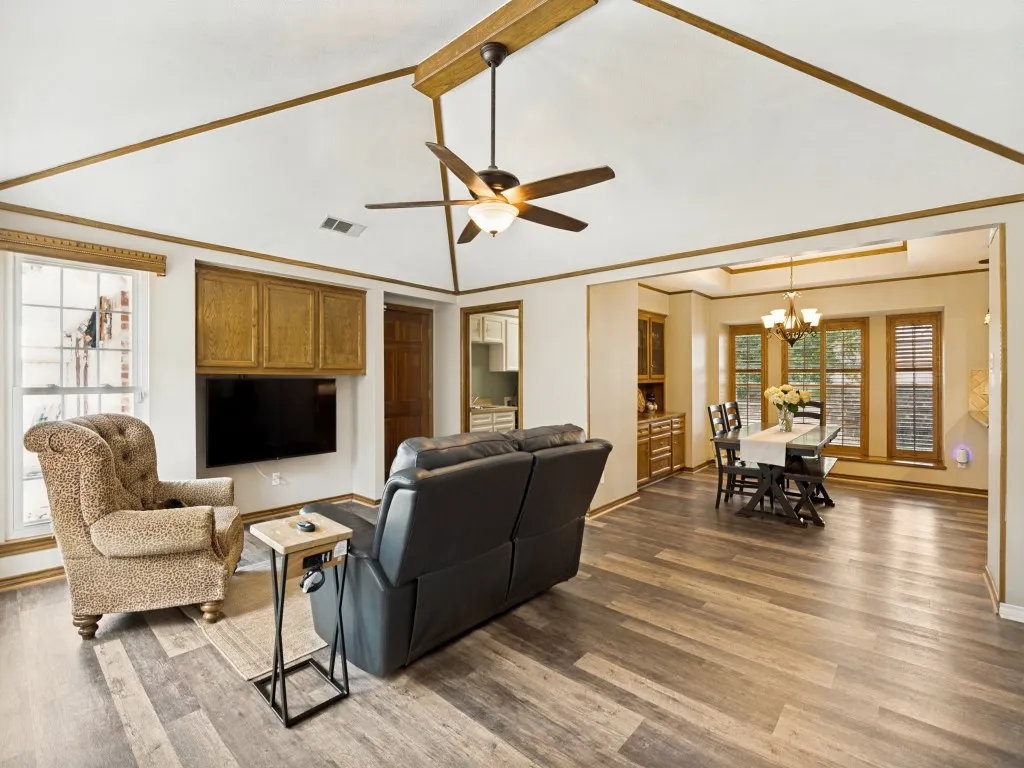 Spacious open-concept living area featuring high vaulted ceilings with wood beams and a ceiling fan