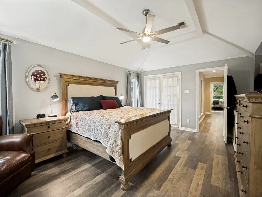 Spacious room featuring wood-finish flooring, a tray ceiling with a modern ceiling fan, and light gray wall paint
