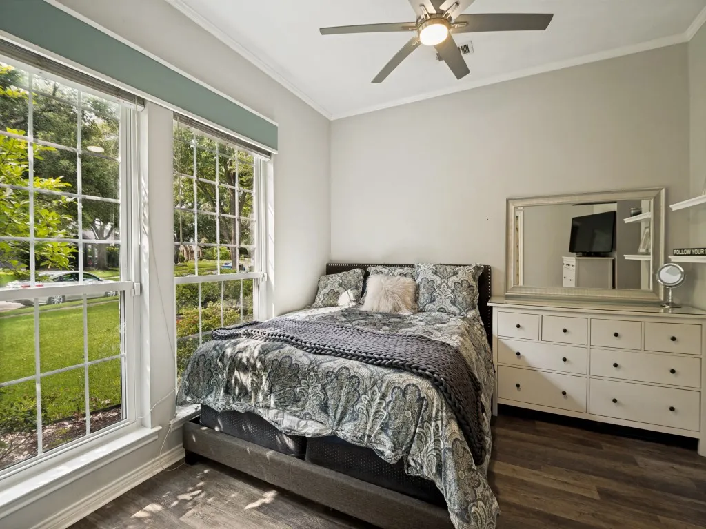 Room featuring wood-finish flooring, a ceiling fan with integrated lighting, and crown molding