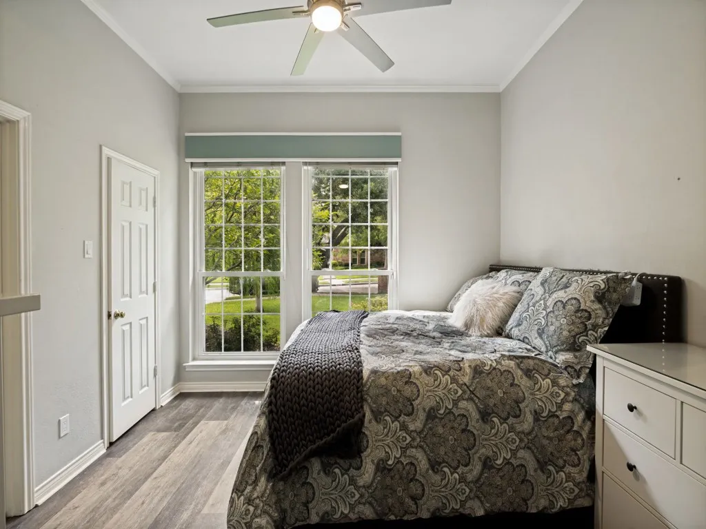 Inviting room featuring wood-finish flooring, dual pane windows, and a ceiling fan with integrated lighting