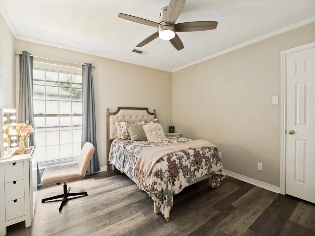 Spacious room featuring wood-finish flooring, a ceiling fan with integrated lighting, and crown molding