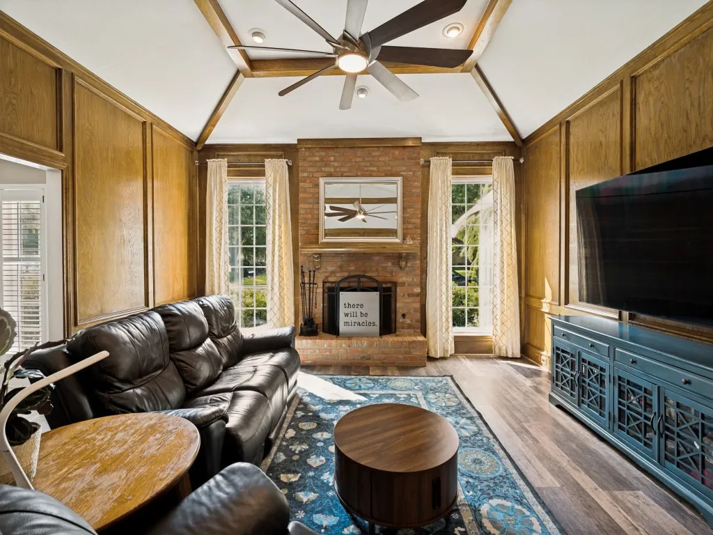 Vaulted ceiling with wood beam accents and a ceiling fan