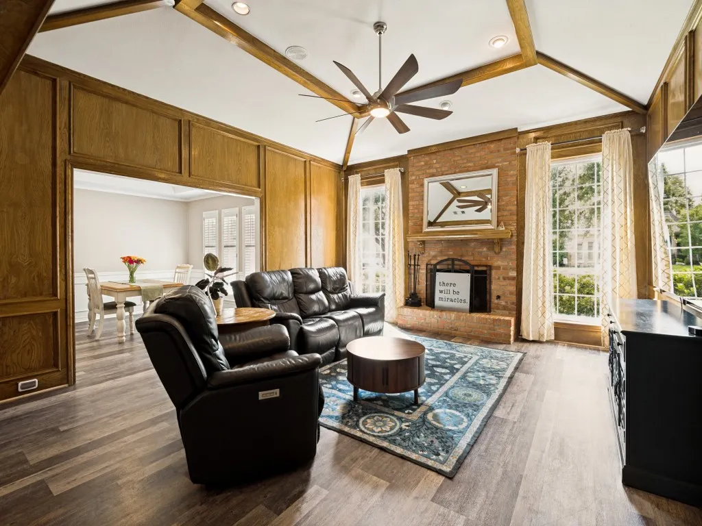 Spacious living area featuring a brick fireplace, wood-finish flooring, and recessed lighting
