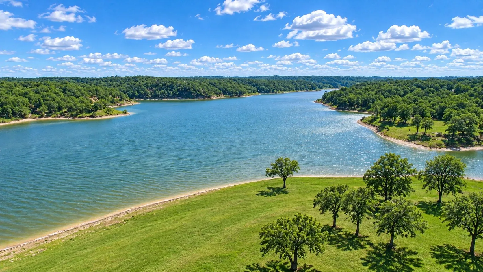 Expansive waterfront property with a verdant shoreline, mature trees, and a clear blue waterway