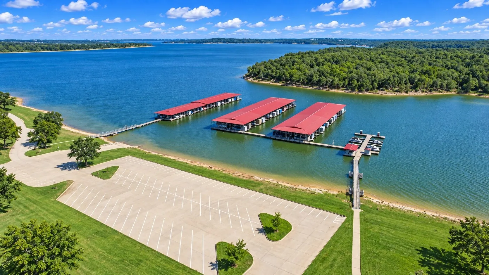 Expansive lakefront property featuring a large parking area, direct water access, three covered boat docks, and a separate boat slip with additional moorings