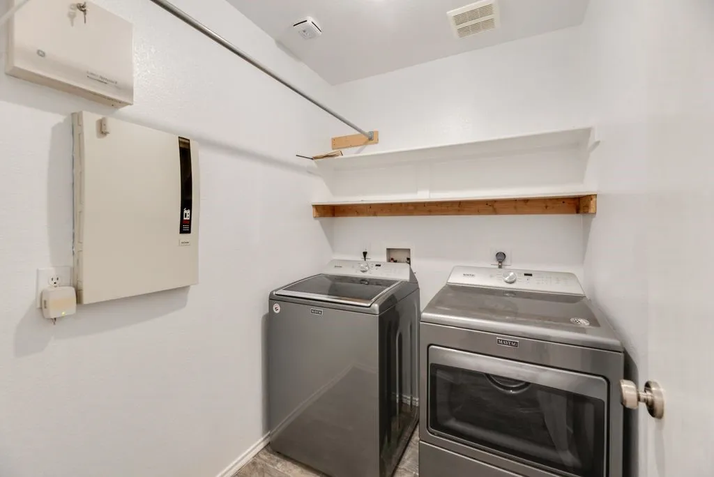 Dedicated laundry area featuring a hanging rod, built-in shelving, and neutral wall finishes