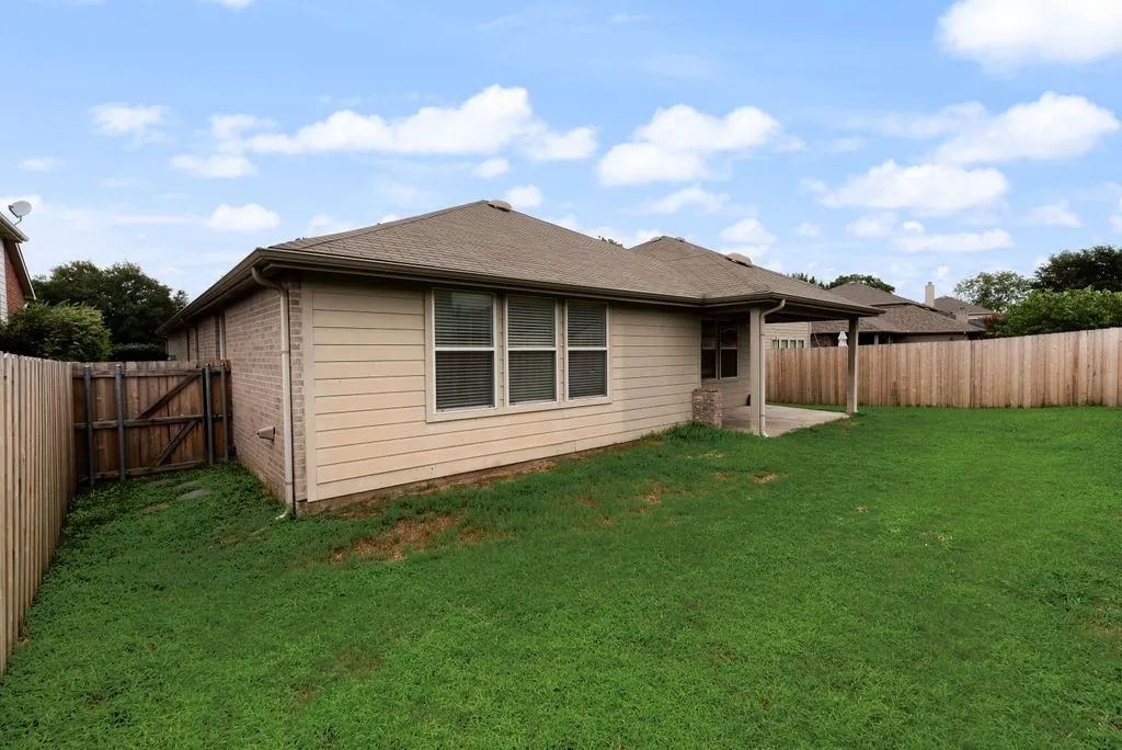 Expansive backyard featuring a covered patio, wood fencing, and a side gate