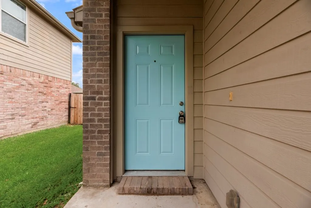 Light blue paneled front door with brick surround, concrete entry, and siding exterior