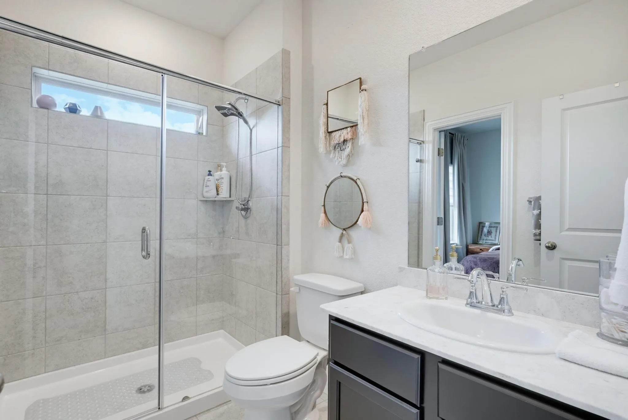 Modern bathroom featuring a glass-enclosed shower with tile surround and a transom window