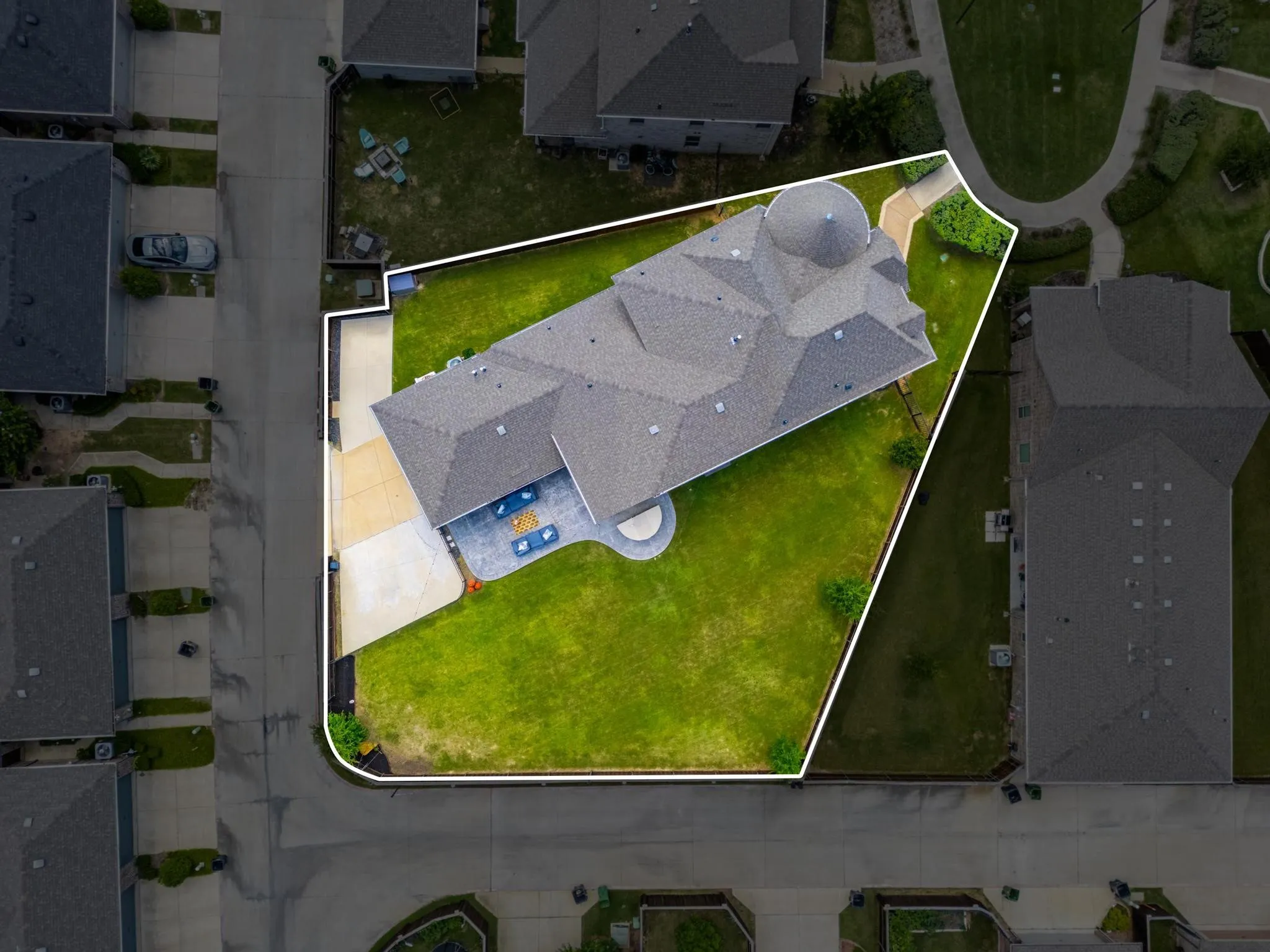Spacious property featuring a large landscaped lawn, an expansive paved patio, and a driveway